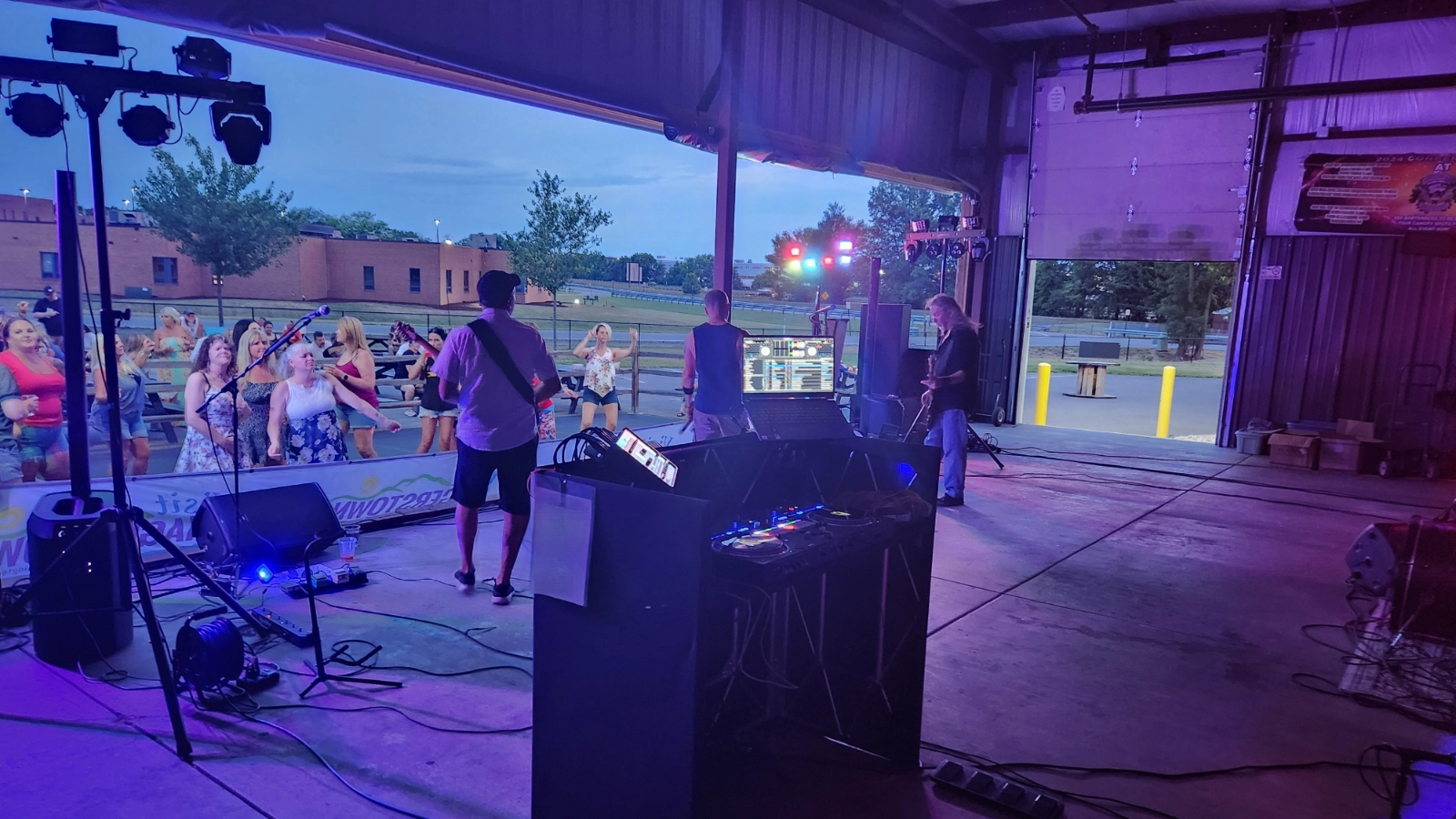 DJ Sideout production equipment, performers, and guests during a live indoor-outdoor event.