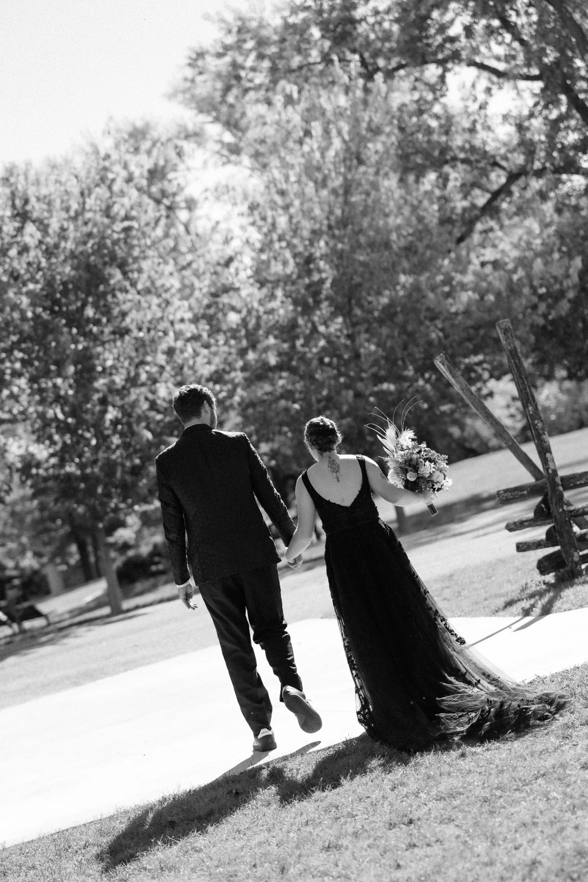 A newlywed couple walking hand in hand outdoors after their wedding ceremony.